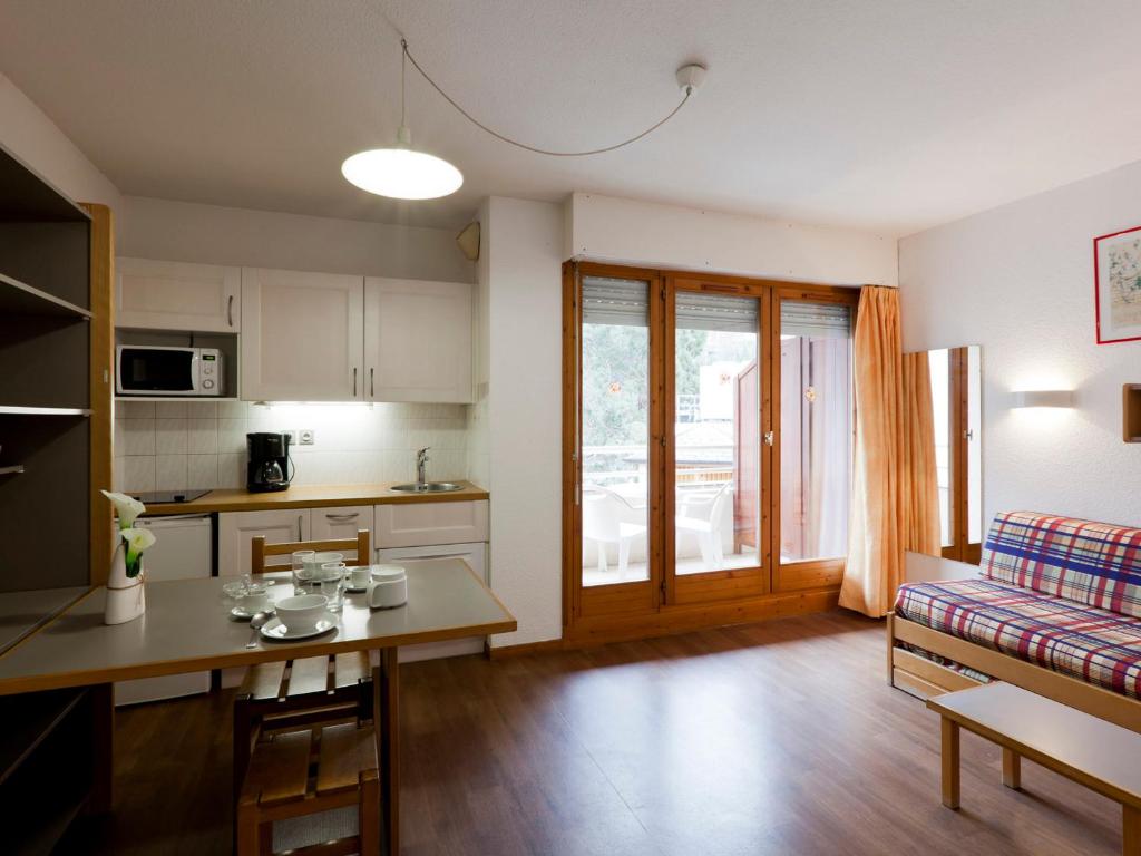 eine Küche und ein Wohnzimmer mit einem Tisch und einer Couch in der Unterkunft Studio Confortable pour 2 Personnes avec Balcon, Proche Télécabine et Spa à Brides-les-Bains - FR-1-512-114 in Brides-les-Bains