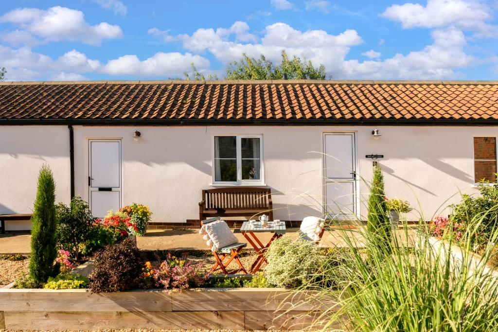 a white cottage with a bench in the garden at Swingletree Cottage in Bridlington