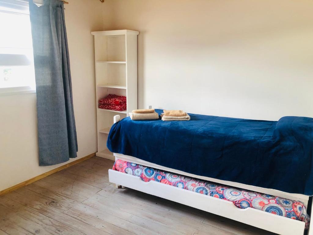 ein Schlafzimmer mit einem Bett mit blauer Bettwäsche und einem Regal in der Unterkunft Casita San Martín in San Martín de los Andes