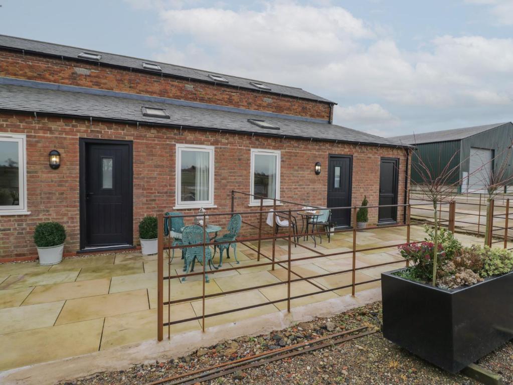 a patio with chairs and tables on a brick building at Pear Barn in Daventry