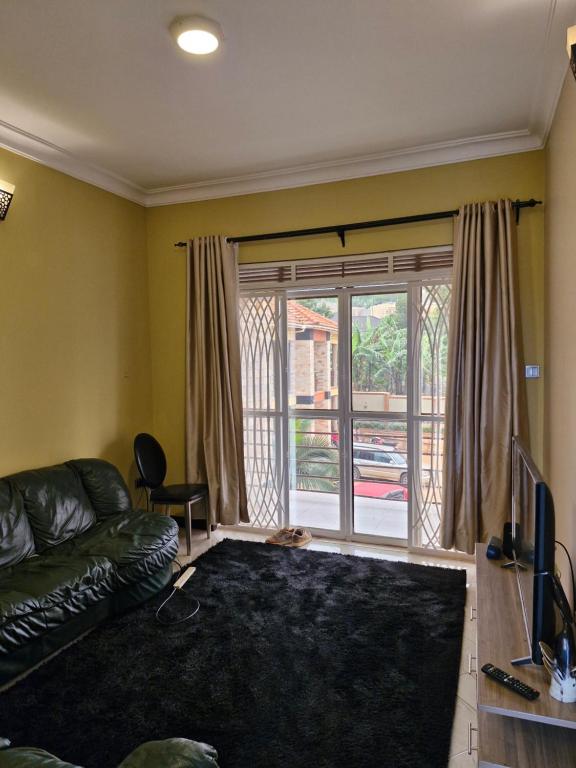 ein Wohnzimmer mit Sofa und Glasschiebetür in der Unterkunft Kyanja Luxury Suites in Kampala