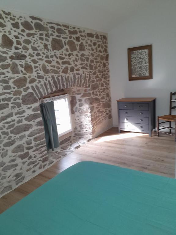 Cette chambre dispose d'une cheminée en pierre et d'une fenêtre. dans l'établissement Gîte familial 8 couchages proche PuyduFou, à Beaurepaire