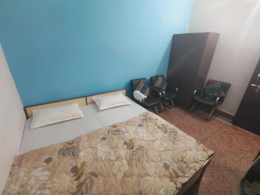 a bedroom with a bed with two chairs and a blue wall at Shree Dhaam Homestay in Faizābād