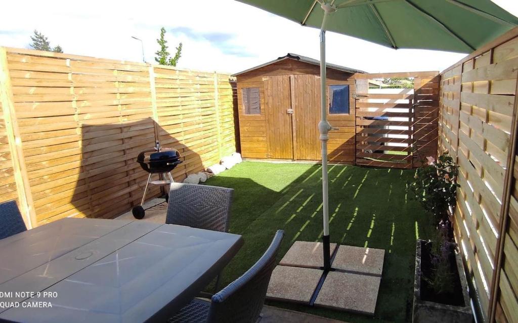 - une terrasse avec une table, un parasol et un grill dans l'établissement Studio en plein cœur du bassin d'Arcachon, à Audenge