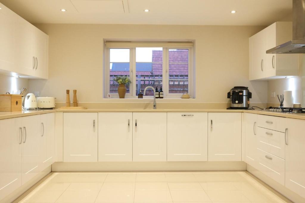 a kitchen with white cabinets and a window at Bicester Villa - 6 Bed - Sleeps 14 in Bicester