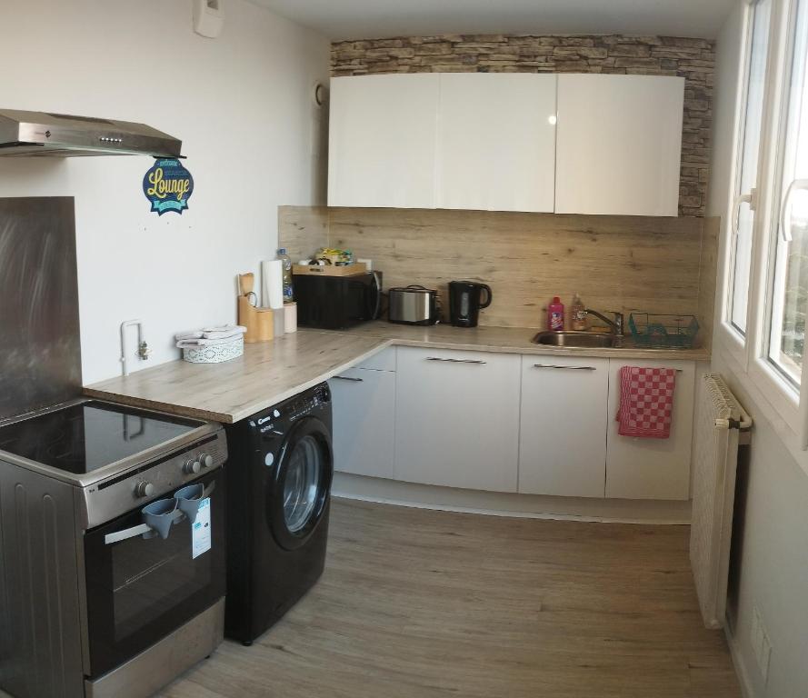 une cuisine avec des armoires blanches et une machine à laver dans l'établissement Parenthèse salée en Côte d'Armor, à Saint-Brieuc