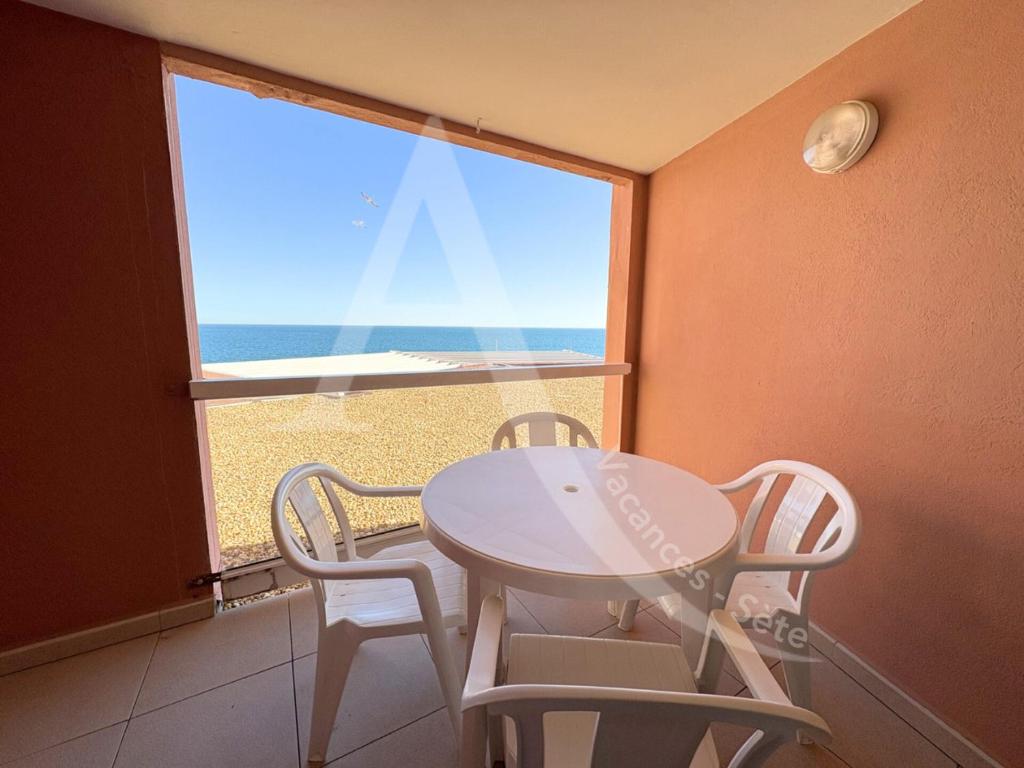 une table et des chaises dans une pièce avec une fenêtre dans l'établissement studio vue mer parking piscine tennis, à Sète