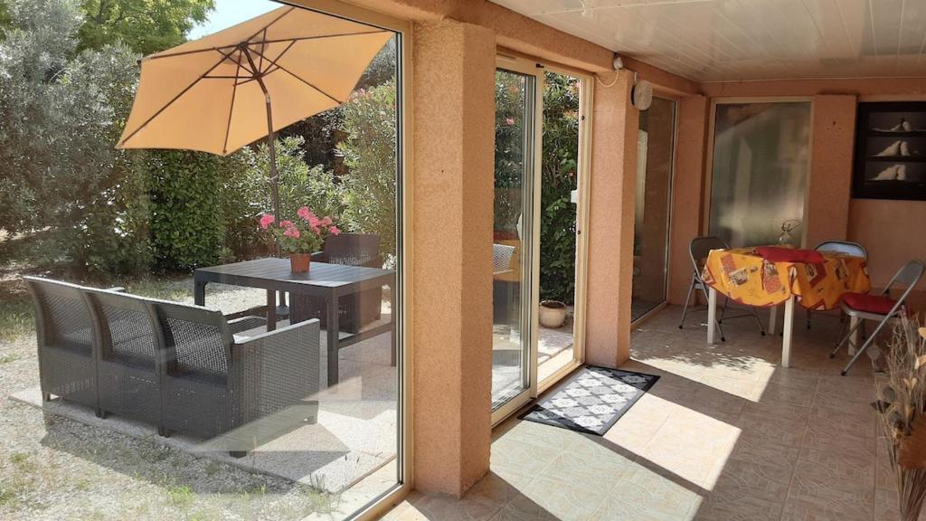 une terrasse avec un parasol et une table avec une table dans l'établissement Les acacias, à Gréoux-les-Bains