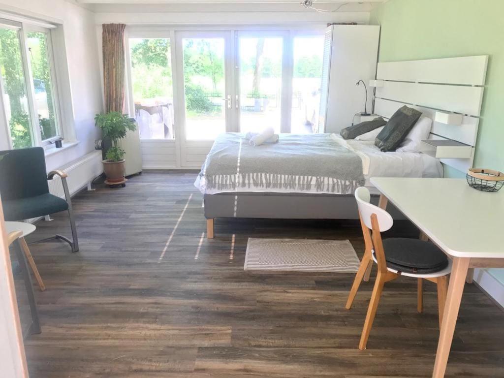 StoutenburgにあるLight tiny house in green area with sauna optionのベッドとテーブルと椅子のある寝室