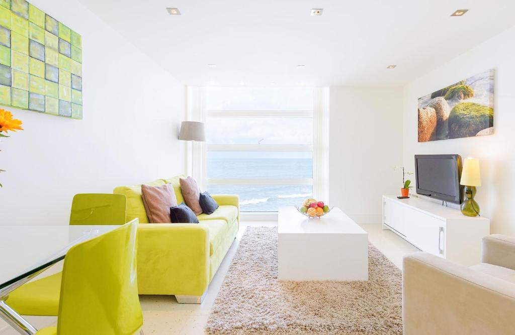 a living room with a yellow couch and a television at 28 Rocklands in Newquay in Newquay