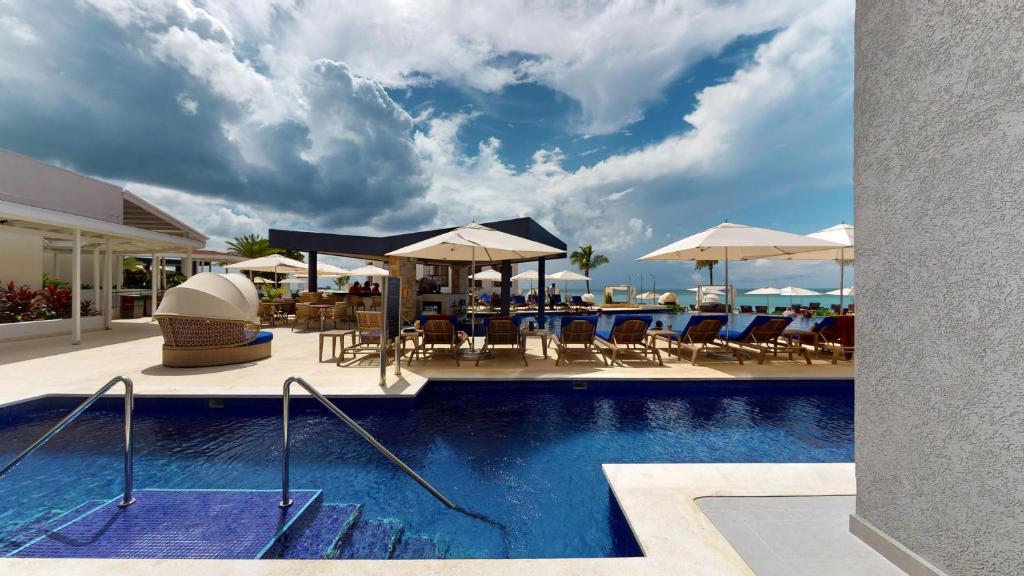 a pool with chairs and tables and umbrellas at Royalton CHIC Antigua, An Autograph Collection All-Inclusive Resort - Adults Only in Saint Johnʼs