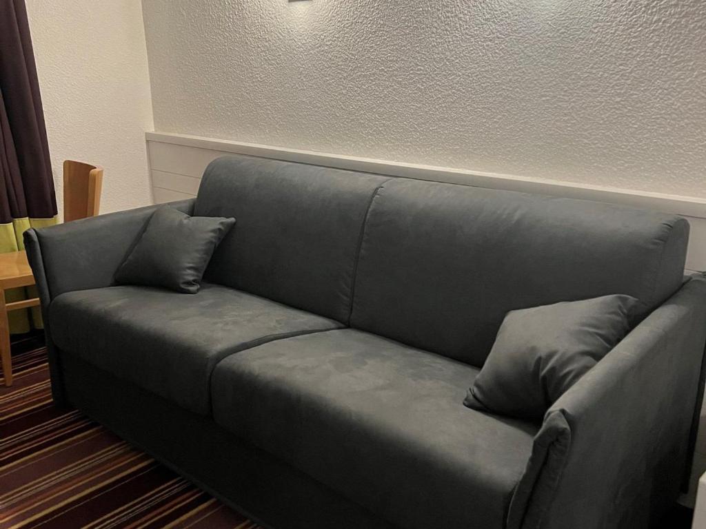 - un canapé gris avec deux oreillers dans le salon dans l'établissement Appartement confortable 2 pièces avec balcon, départ skis aux pieds, Wifi inclus - FR-1-314-213, à Morzine