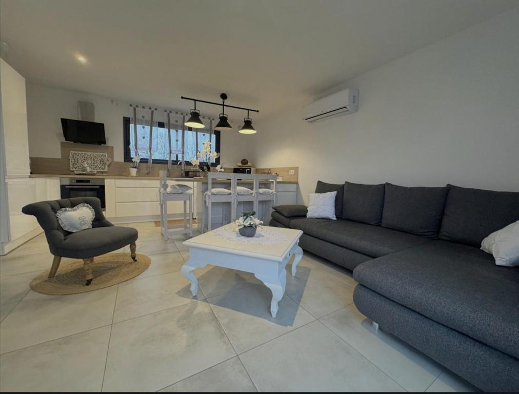 una sala de estar con un sofá y una mesa en Dépendance de charme, en Ruaudin