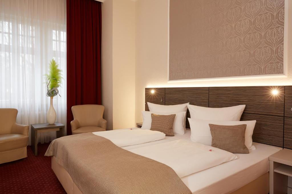 una habitación de hotel con una cama grande y una silla en Hotel Prinzregent en Núremberg