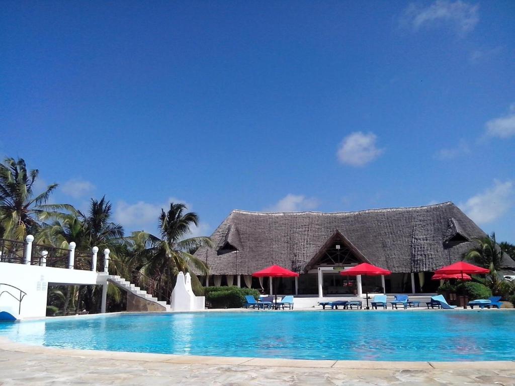a resort with a swimming pool and red umbrellas at Karibuni in Malindi