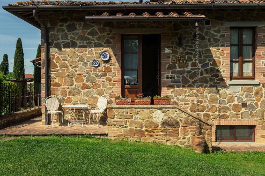 Maison en pierre avec 2 chaises et une table dans l'établissement La Pergola, à Lucignano