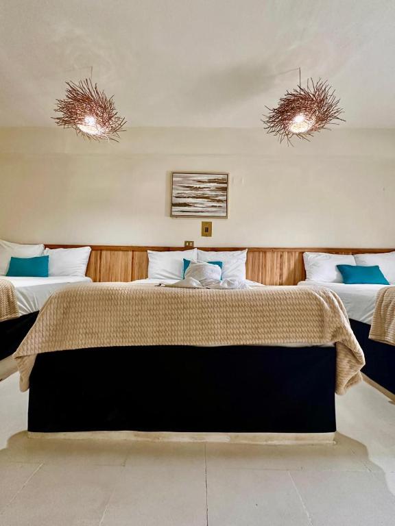 a bedroom with two beds and two lights on the ceilings at Hotel cacao spa cozumel in Cozumel