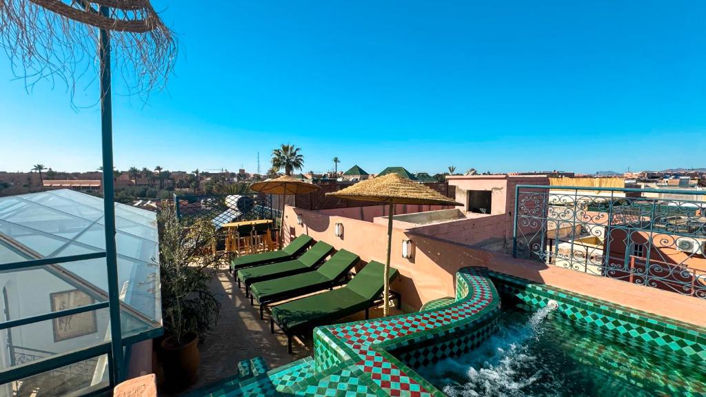 ein Swimmingpool mit grünen Liegestühlen und einem Swimmingpoolvisor in der Unterkunft Riad Abi in Marrakesch