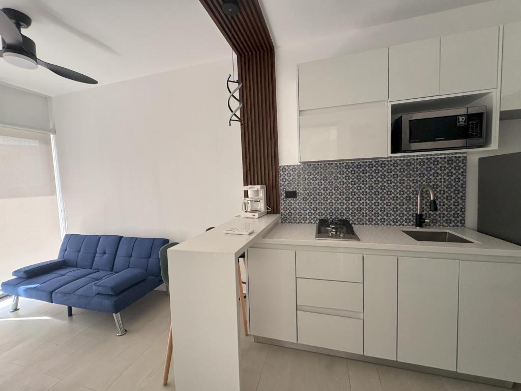 a kitchen with white cabinets and a blue chair at Ocean Dream Apartments E1-A1 in San Juan del Sur