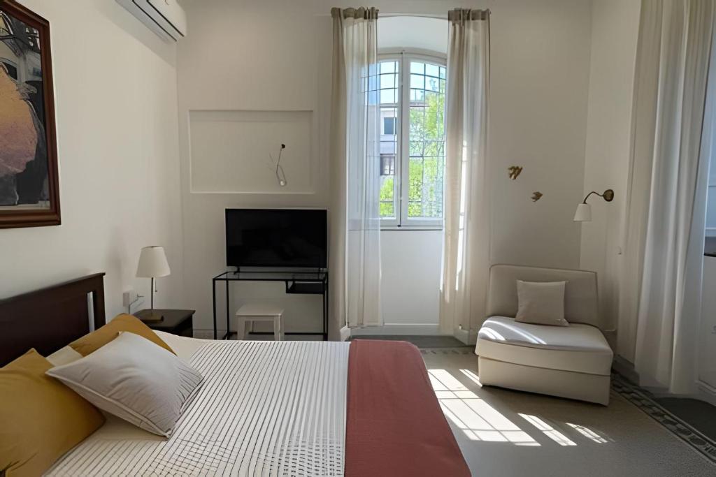 Un dormitorio blanco con una cama y un televisor. en Camera doppia con Aria condizionata e Parcheggio accanto gratuito a 5 min dal Lucca Summer Festival, en Lucca