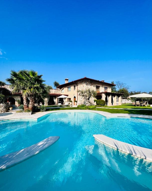 a large swimming pool with two chairs in front of a house at Villa Mario Resort in Salò