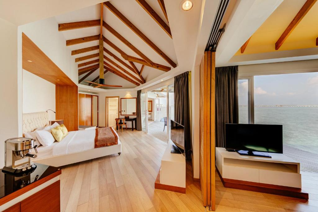 a bedroom with a bed and a tv in a room at Cinnamon Dhonveli Maldives in North Male Atoll