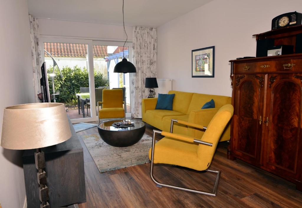 a living room with a yellow couch and chairs at Ferienhaus ,Felix' in Heiligenhafen