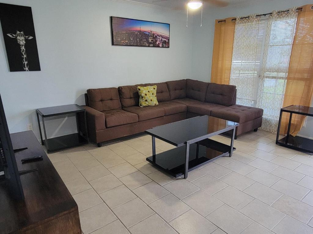 ein Wohnzimmer mit einem braunen Sofa und einem Tisch in der Unterkunft Secret Cajun Retreat Peaceful Corner Stay - HAR 2 in Iowa