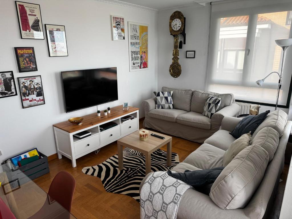 un salon avec deux canapés et une télévision à écran plat dans l'établissement El Rincón del Reloj, à Llanes