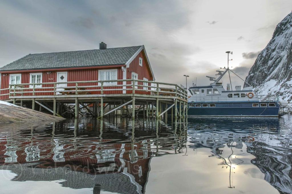 a boat is docked next to a house on a dock at Maybua by May's in Reine