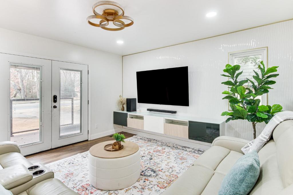 a living room with a white couch and a flat screen tv at 6 Mi to Spectrum Center: Spacious Getaway w/ Deck in Charlotte