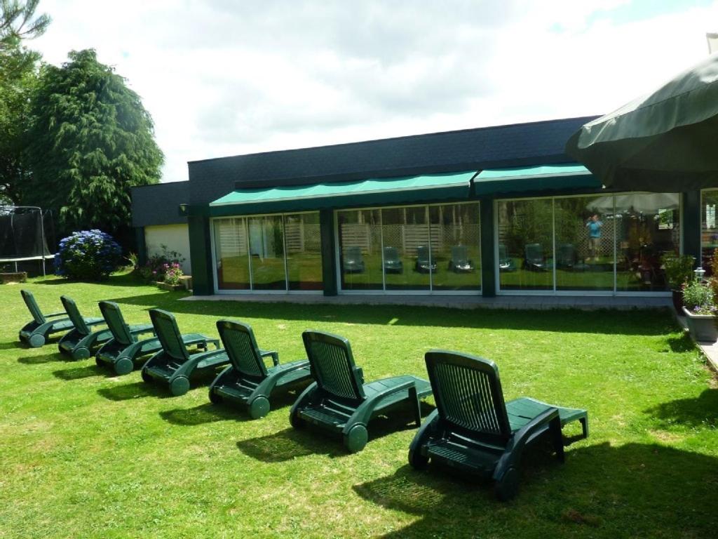 a row of chairs sitting in the grass in front of a building at Country home with indoor pool 20 pers in Cléguérec