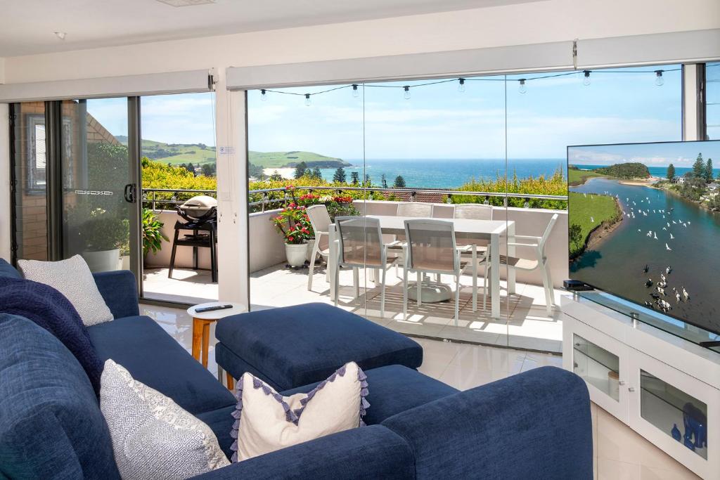 a living room with a blue couch and a tv at Burri Burri View for 2 people- Ocean Views in Gerringong