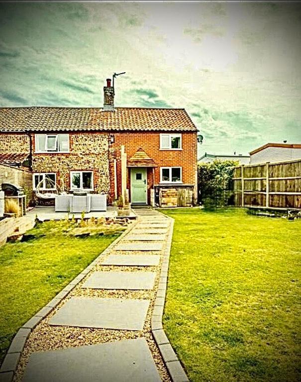 a stone pathway leading to a brick house at April Cottage in Bacton