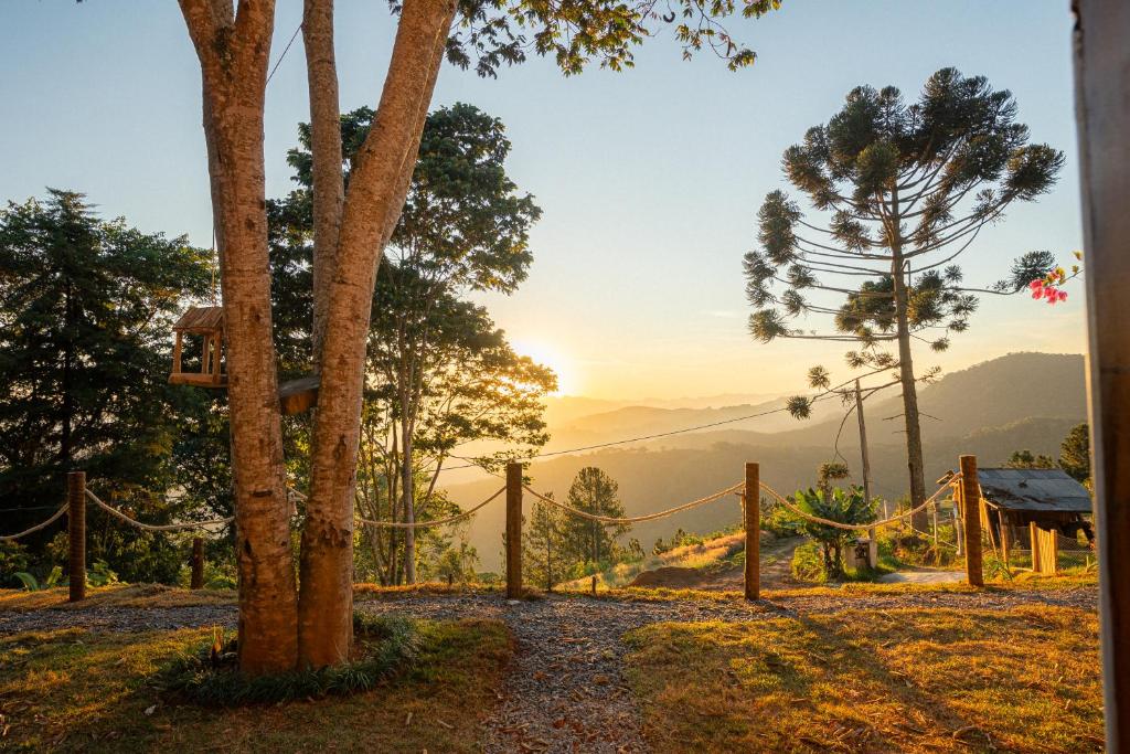 ein Kreuz, das an einem Baum neben einem Zaun hängt in der Unterkunft Chalé Sunset Hills em Campos do Jordão in Campos do Jordão