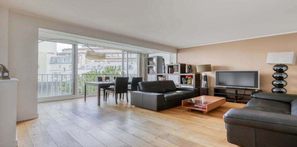 un salon avec un canapé et une table avec des chaises dans l'établissement Spacious Contemporary Flat in the 15th - Mid-T, à Paris