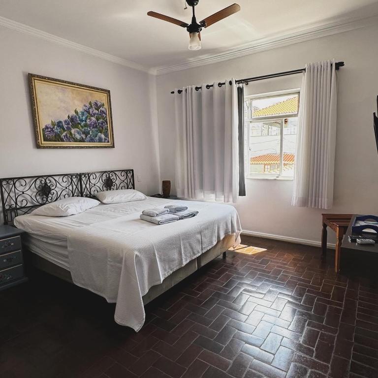 a bedroom with a large bed and a window at Pousada Minha Casa- Aconchegante no Centro de São Lourenço in São Lourenço