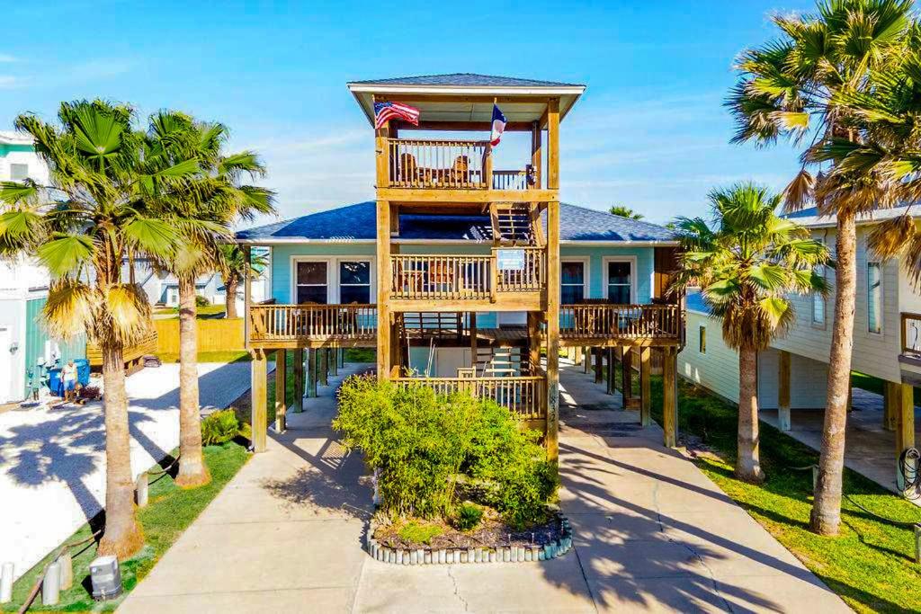 a house with a deck with palm trees at Casa Playa - Ocean Views Pet Friendly Boardwalk in Port Aransas