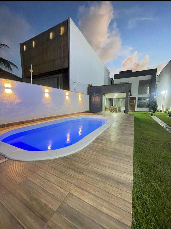 a swimming pool in front of a house at Mansão Climatizada com piscina e churrasqueira in Camaçari