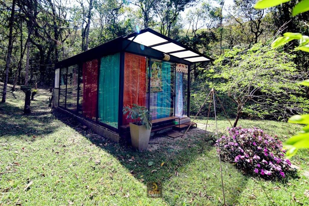 a colorful greenhouse in a yard with a potted plant at Nirvana Glamping, Nature Glass Chalet in São Francisco Xavier