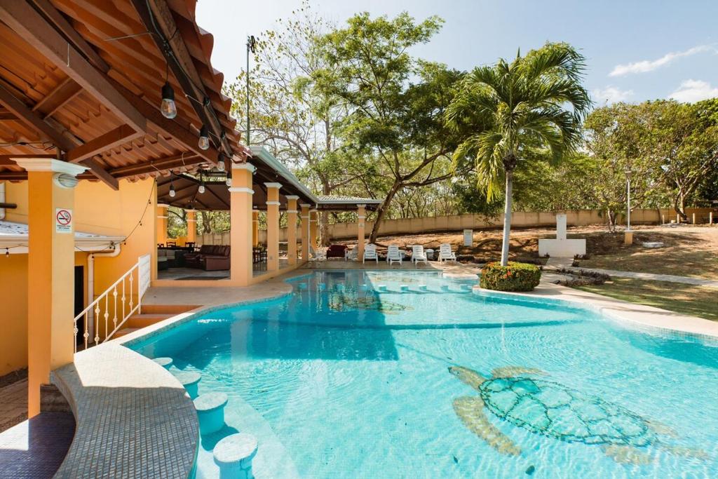 a swimming pool in a resort with chairs and trees at Villa Jr 3 near the peñon guacalillo in Tarcoles