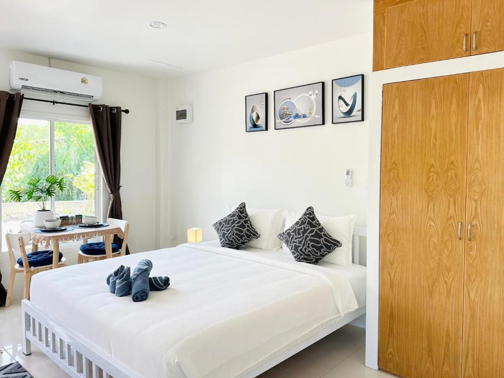 Sachi House Stay Near Muay Thai Gym and Beach في Ban Thalat Choeng Thale: غرفة نوم بيضاء مع سرير مع دبتين عليه