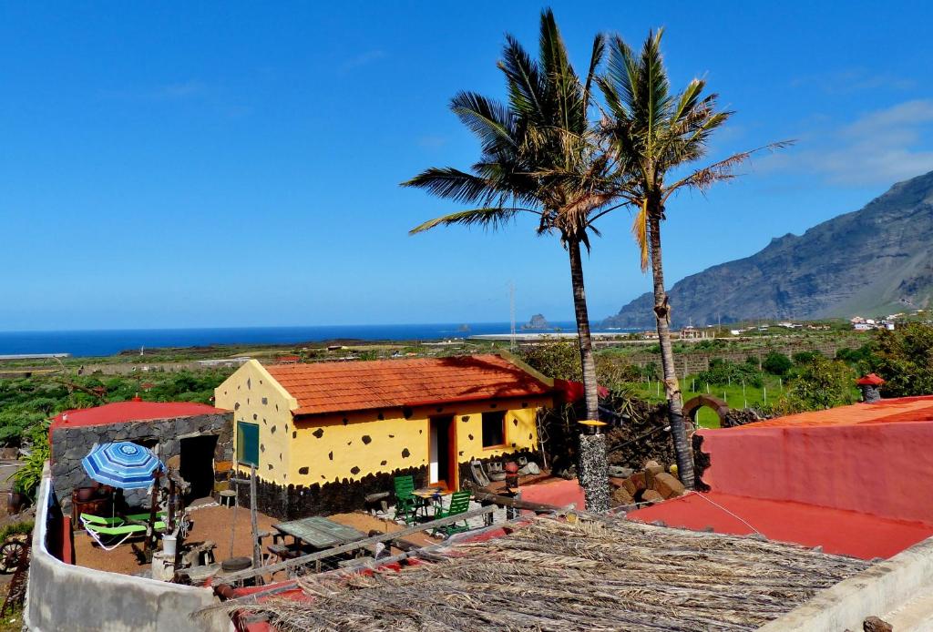 una casa amarilla con una palmera y el océano en Casa Guinea en Frontera