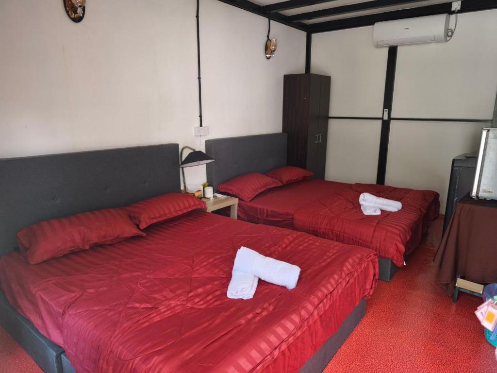 two beds with red sheets and white towels on them at Belibis Yard in Kampar