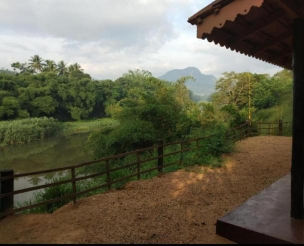 Una valla con vistas a un río y árboles. en Kandy Okaya, en Kandy