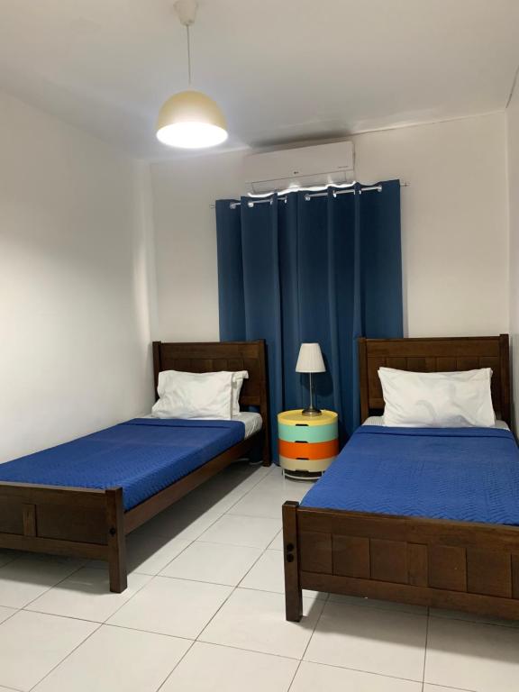 2 letti in una camera con tende blu di The Barkly House Staycation a Biñan
