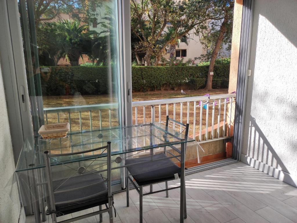 d'une table en verre et de deux chaises sur un balcon. dans l'établissement Appartement 2 pièces près plage avec parking sécurisé - FR-1-776-124, à Argelès-sur-Mer