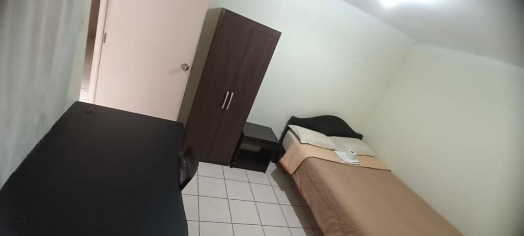 a small bedroom with a bed and a cabinet at Hostal Caxamarcorco in Cajamarca