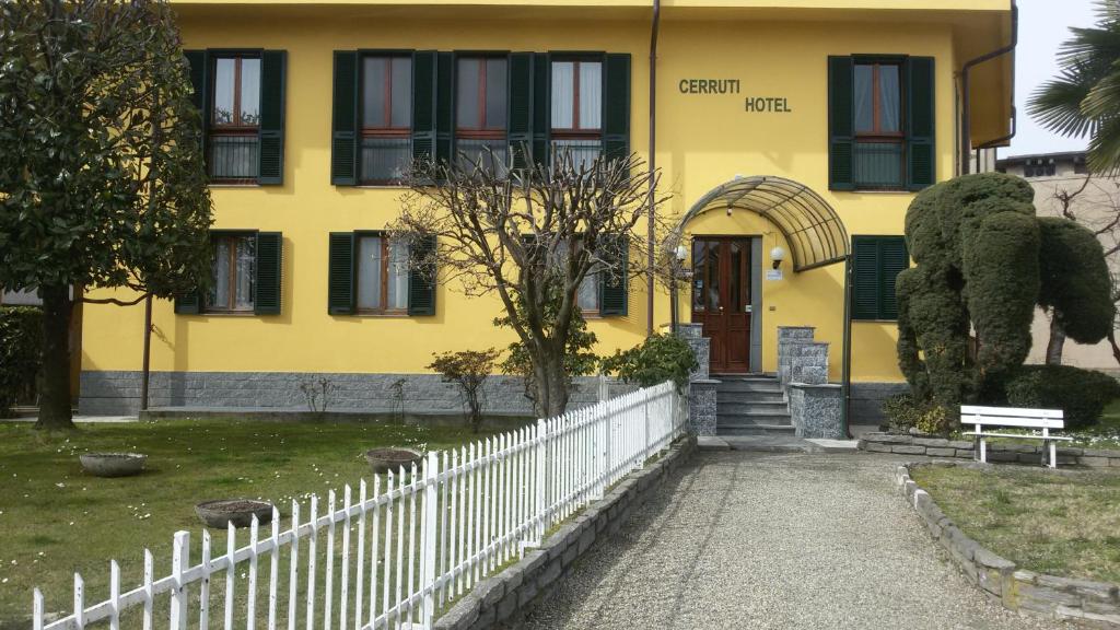a yellow building with a white fence in front of it at Cerruti Hotel in Vercelli