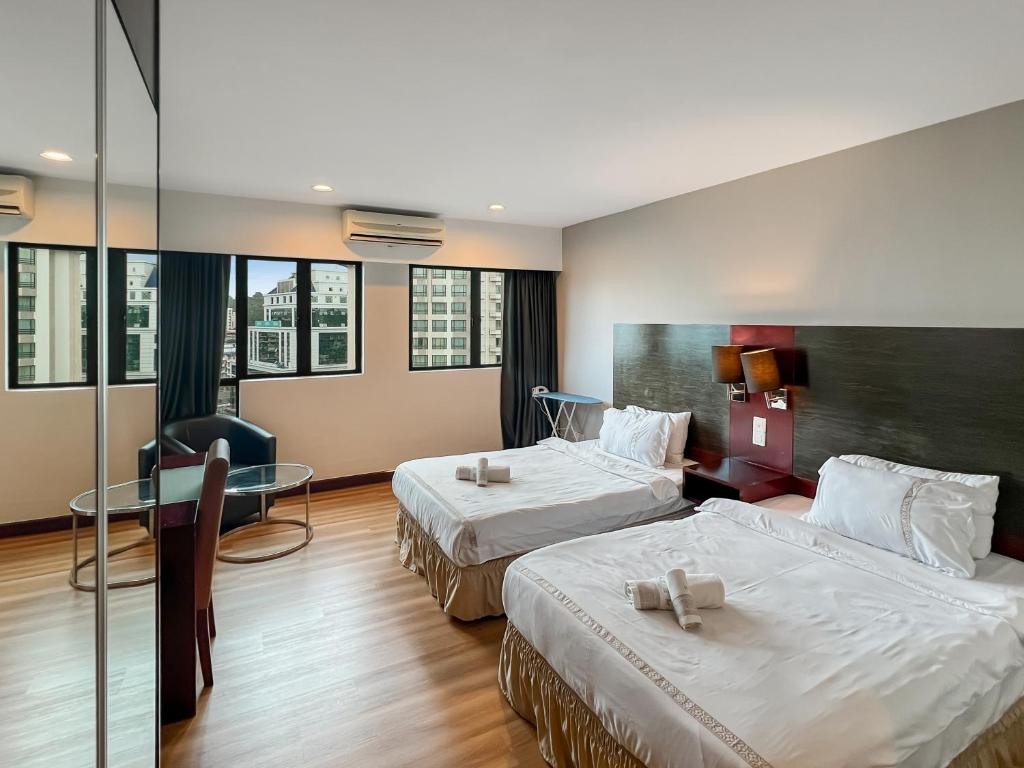 una camera d'albergo con due letti e un tavolo di Royal Crown Scsp KK CBD near Imago a Kota Kinabalu